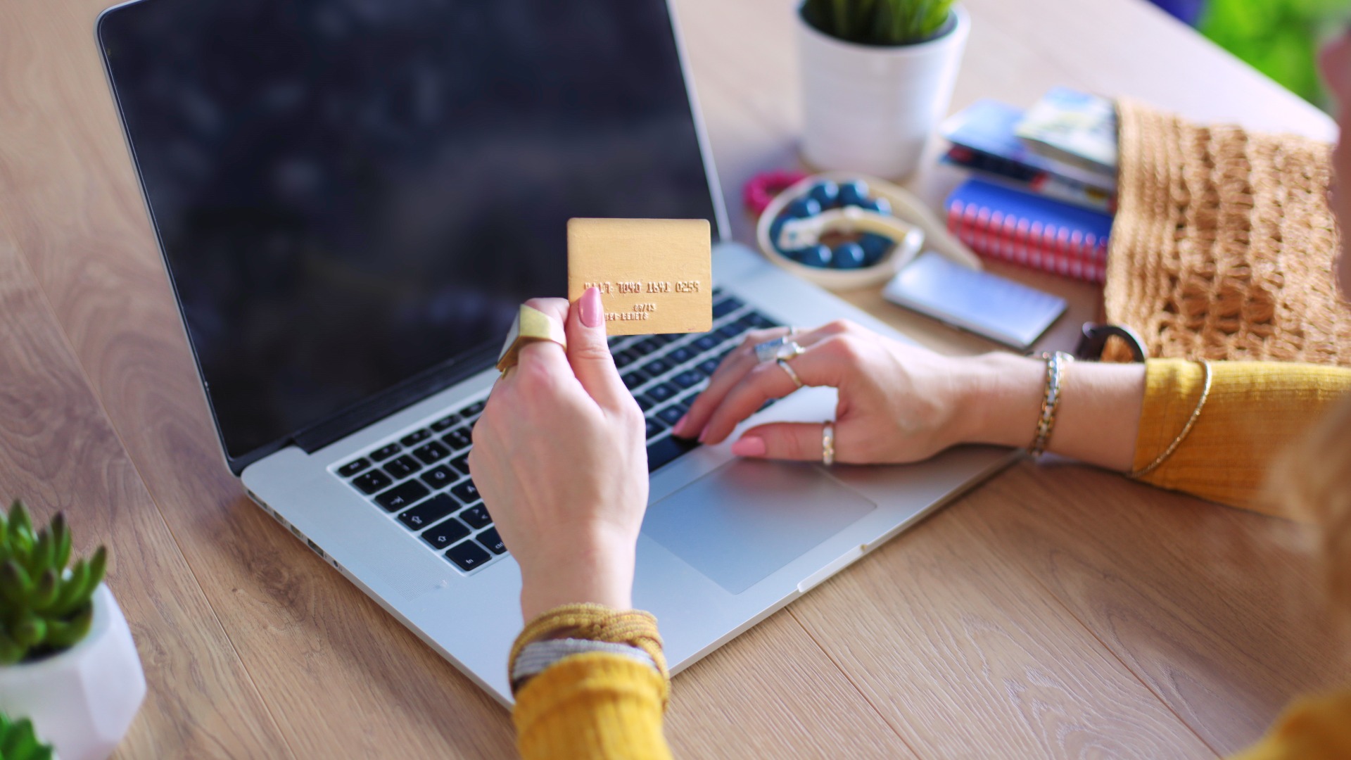 woman holding a credit card in front of a laptop